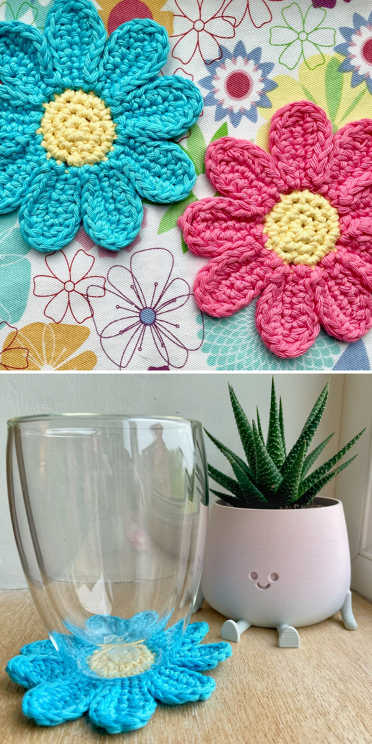 Blue and pink crochet daisies with yellow centers rest on a patterned surface. Below, a clear drinking glass stands above a blue daisy coaster beside a small plant. Thick petals and visible stitches create a cheerful flower shape.